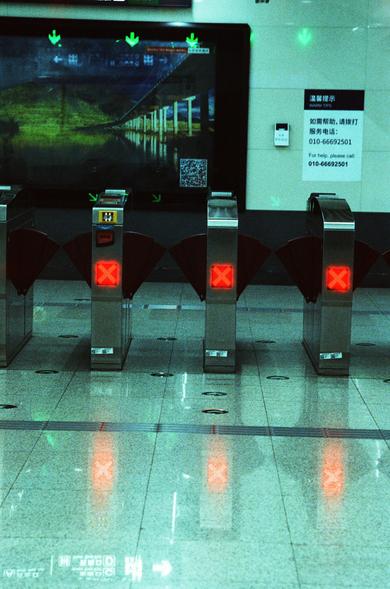 CineStill 800T (FF)

English Alt Text
A row of automated subway turnstiles indoors, each displaying a red “X” indicating they are not in service. Above them is a large illuminated display showing a scenic image of a bridge with green downward arrows. To the right, a sign provides assistance information in Chinese and English, including a phone number. The station appears clean and quiet, with no passengers visible.
中文替代文字
一排地铁闸机整齐排列在室内，每个闸机上方都亮着红色“X”，表示暂不可通行。闸机上方是一块大型发光屏幕，显示着一幅桥梁风景图，并配有绿色向下箭头。右…