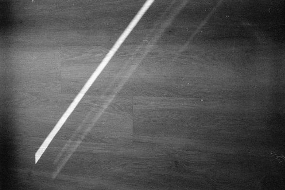 Ilford HP5 Plus 400 (FF)

English alt text:
A dark wooden floor seen from above, with a narrow diagonal beam of bright light cutting across the surface from the lower left to the upper right. A faint secondary reflection or shadow runs parallel to the main beam. The contrast between the illuminated strip and the surrounding darkness creates a minimalist, quiet atmosphere. No objects or people are present.
中文替代文字：
从上方俯视一片深色木地板，一束细长而明亮的光线以对角线方式从左下延伸到右上。旁边有一条较淡的反射或阴影与光束平行。明暗对比强烈，画面简洁安静，没有任何物体或人物。