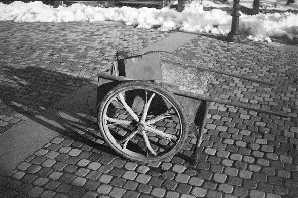 Ilford FP4 Plus 125 (FF)

English alt text
A black‑and‑white image of an old wooden handcart with large spoked wheels positioned on a cobblestone street. The cart appears weathered. Snow is piled along the edge of the street. A streetlamp stands in the background, casting shadows. The scene has a quiet, historical atmosphere.
中文替代文字
一张黑白照片，画面是一辆老式木制手推车，带有大号辐条轮，停放在鹅卵石街道上。手推车显得陈旧。街道边缘堆着积雪。背景有一盏街灯，投下阴影。整体呈现安静而带有历史感的氛围。