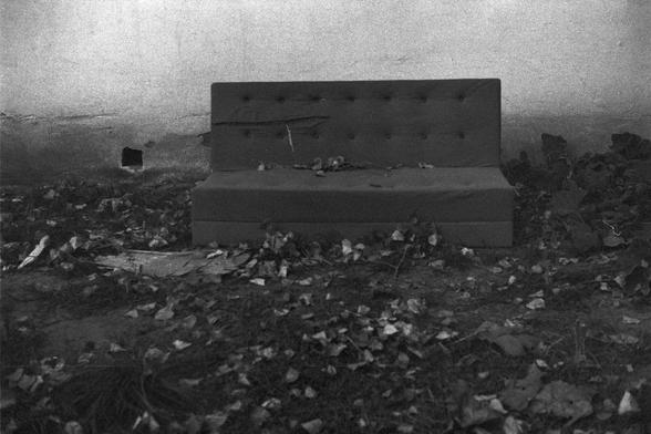 Ilford FP4 Plus 125 (FF)

English: A black-and-white photograph of a discarded sofa placed on a rocky, debris-covered ground. The sofa is upright, with visible tufted buttons on its backrest. The surroundings appear cluttered with rocks and scattered debris.

中文: 这是一张黑白照片，照片中一个被遗弃的沙发放置在布满岩石和碎片的地面上。沙发直立着，其靠背上可见钉纽装饰。周围环境看起来杂乱，有岩石和散落的碎片。