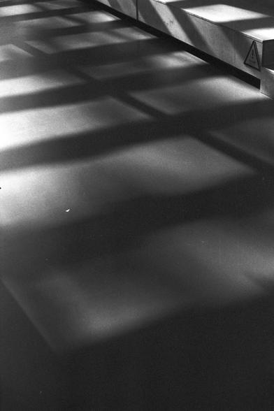 Ilford FP4 Plus 125 (FF)

English:
A black-and-white photograph showing a risen platform with strong shadows cast and adjacent wall. The shadows create a geometric pattern, emphasizing the contrast between light and dark areas.

Mandarin Chinese:
一个黑白照片，展示了抬高的平台及其在台阶和相邻墙壁上的强烈阴影。阴影形成几何图案，强调了光线与黑暗区域的对比。
