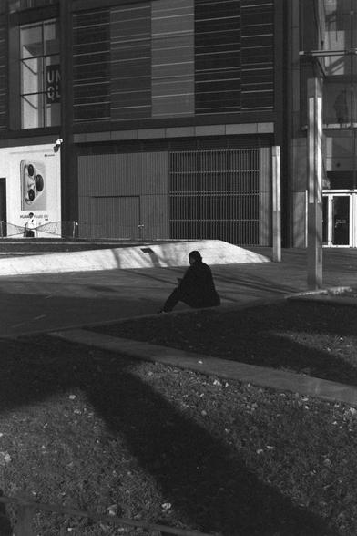 Ilford FP4 Plus 125 (FF)

Image 4:
This black-and-white photograph captures a person sitting alone on a low wall or ledge in an urban setting. The person is silhouetted against a modern building in the background, which features large windows and a sleek design. The scene is peaceful, with a sense of solitude and contemplation.

中文:
这张黑白照片拍摄的是一个独自坐在城市低墙或台阶上的人。人物被背景中一栋现代建筑的剪影衬托，这栋建筑有大面积的窗户和简洁的设计。场景宁静，带有一种孤独和沉思的氛围