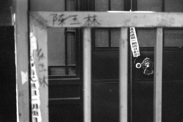 Ilford FP4 Plus 125 (FF)
English:

This is a black-and-white photograph of a metal gate with vertical bars. A paper seal with Chinese characters is attached to the bars.
普通话:

这是一张黑白照片，照片中是一个带有垂直金属条的金属门。门上贴有封条。