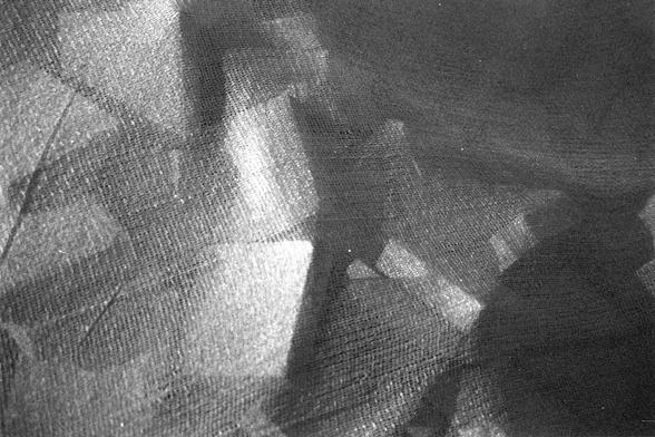 Ilford FP4 Plus 125 (FF)

##English

A black-and-white close-up photograph of a woven mesh or netting material. The mesh is draped in folds, creating sharp geometric shadows and highlights. The texture and pattern of the mesh are clearly visible.

##中文

一张黑白照片，展示了编织网或网状材料的特写。网状物折叠形成锐利的几何阴影和高光，网状物的纹理和图案清晰可见。