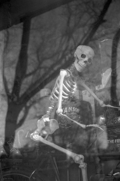 Ilford FP4 Plus 125 (FF)

English

A black-and-white photograph of a human skeleton model posed as if riding a motorcycle. The skeleton is in front of a dark jacket with the word "ANSON'S" visible on the back, and it is seated on what appears to be a motorcycle seat. The background is blurred, but it suggests a dark, draped setting, possibly part of a display or exhibit.

中文

一张黑白照片，拍摄的是一个骷髅模型，姿势仿佛在骑摩托车。骷髅在一件深色夹克的前方，背部可见“ANSON'S”字样，坐在类似摩托车座位的物体上。背景模糊，但可以看出是一个黑暗、布幕环绕的场景，可能是某个展示或展览的一部分。