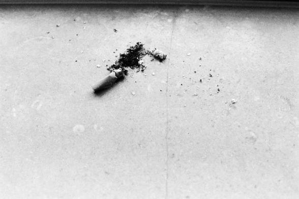 Lucky LUCKY SHD 400 (FF)
##English

A black-and-white close-up photograph of a crushed cigarette butt and a small pile of ash on a flat, light-colored surface. The cigarette butt is partially crushed, and ash is scattered around it.

##中文

一张黑白特写照片，拍摄的是一个被压扁的香烟头和一小堆烟灰，散落在平整的浅色表面上。香烟头被部分压碎，周围散落着烟灰。