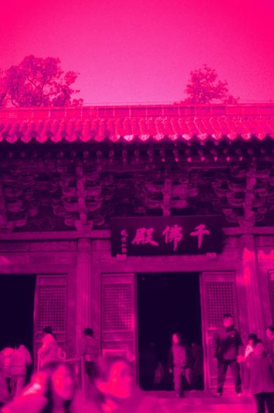 Harman Red 125 (FF)

English

A traditional building entrance with a signboard displaying Chinese characters. The building has a tiled roof and ornate doors. Several people are entering or standing near the entrance. The scene is bathed in a pinkish-red tint, and trees are visible in the background.

中文

一栋传统建筑的入口处挂着一个写有中文字的牌匾。建筑物有瓦片屋顶和精美的门。几个人正在进入或站在入口附近。整个场景被粉红色调覆盖，背景中可以看到树木。