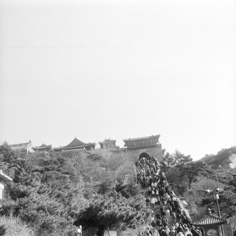 Lucky LUCKY SHD 400 (6x6)

English

A black-and-white photograph of a large, traditional Chinese building complex situated on a hillside. The buildings have classic Chinese architectural features, including upturned eaves and tiled roofs. In the foreground, there is a steep staircase with many people ascending. The hillside is covered with trees and shrubs.

中文

一张黑白照片，拍摄的是一座位于山坡上的大型传统中国建筑群。建筑物具有经典的中国建筑特色，包括翘起的屋檐和瓦屋顶。前景中有一条陡峭的楼梯，许多人正在攀登。山坡上覆盖着树木和灌木。