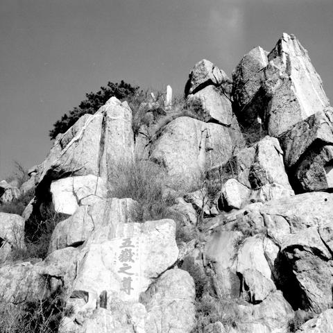 Lucky LUCKY SHD 400 (6x6)

English

A black-and-white photograph of a rocky hillside. The hill is covered with large, jagged rocks and boulders. On one of the rocks, there is Chinese text carved into the surface. The text reads "五嶽之尊." The background shows some sparse vegetation and a clear sky.

中文

一张黑白照片，拍摄的是一个多岩的山坡。山坡上布满了大大小小的岩石和巨石。其中一块岩石上雕刻着汉字“五岳之尊”。背景中可以看到稀疏的植被和晴朗的天空。