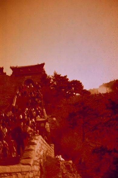 Harman Red 125 (FF) 

English

A vintage-style photograph with a red tint, depicting a large group of people ascending a staircase that leads up a hillside. The staircase is flanked by traditional-style buildings and lush greenery. The sky is a light orange hue, creating a warm and nostalgic atmosphere. The focus is on the crowd and the architectural elements, suggesting a popular or historic site.

中文

一张带有红色调的复古风格照片，描绘了一大群人正沿着山坡上的楼梯攀登。楼梯两侧是传统风格的建筑和茂盛的绿色植被。天空呈现出浅橙色，营造出温暖而怀旧的氛围。画面重点展现了人群和建筑元素，暗…