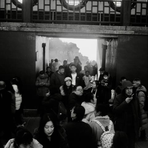 Lucky LUCKY SHD 400 (6x6)

English

A black-and-white photograph shows a crowd of people gathered at the entrance of a historical or cultural site. The entrance is framed by a large, traditional Chinese-style gate with a tiled roof and wooden beams. Above the crowd, a stonewall with Chinese characters is visible. The people are dressed in winter clothing, suggesting a cold day. Some are looking at their phones, while others are conversing or looking ahead.

中文

这张黑白照片展示了一群人聚集在中国某历史或文化景点的入口处。入口由…