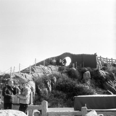 Lucky LUCKY SHD 400 (6x6)

English

A black-and-white photograph of a group of people on a rocky hillside. The hillside is steep and covered with large rocks. In the background, there is a structure with a circular pass through, possibly a pavilion or lookout point, accessible via a path with railings. Two people stand in the foreground, engaged in conversation, while others are seen walking or standing on the path.

中文

一张黑白照片，展示了一群人在多岩石的山坡上。山坡陡峭，布满大石头。背景中有一个带圆形的建筑，可能是亭子或观景台，通过带栏杆的小路可以到达。前景中有两…