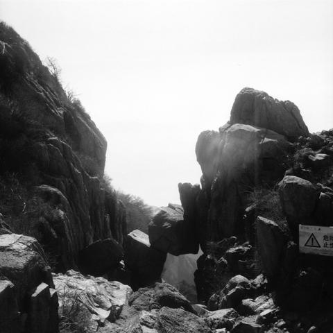 Lucky LUCKY SHD 400 (6x6)

English

A black-and-white photograph of a rocky mountain path. The scene features steep, jagged rock formations on both sides, creating a narrow passage. Sunlight filters through the rocks, casting light and shadow. On the right side, there is a warning sign with a triangle and Chinese text that reads "危险 止步" (Danger, Do Not Enter).

中文

一张黑白照片，展示了崎岖的山路。两侧是陡峭的岩石，形成狭窄的通道。阳光透过岩石缝隙，投射出光影效果。右侧有一个警示牌，上面有三角形标志和中文“危险 止步”。