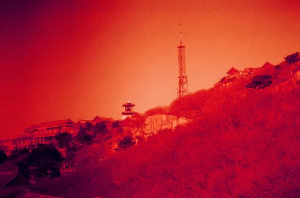 Harman Red 125 (FF)

English

A red-tinted photograph of a hillside landscape. In the center, a tall radio or communication tower stands prominently against the sky. Below the tower, a cluster of buildings with traditional East Asian architectural features, such as curved roofs, are nestled among trees. The overall scene is bathed in a warm red glow, giving it a nostalgic and tranquil ambiance.

中文

一张带有红色色调的山坡风景照。画面中央，一座高耸的无线电或通信塔矗立在天空下。塔下，一群具有传统东亚建筑特色（如曲线屋顶）的建筑坐落在树木之间。整个场景沐浴在温暖的红色光芒中，营造出怀旧而宁静…