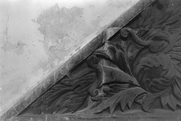 ERA 100 (FF)

English

A black-and-white close-up photograph of an ornate architectural detail. The image shows a carved corner decoration featuring intricate leaf and floral motifs. The carving is detailed, with layers of leaves and scrollwork, and the corner appears slightly worn, with some paint peeling off the adjacent wall.

中文

一张黑白近景照片，展示了精美的建筑装饰细节。图片展示了一个雕刻精细的角落装饰，带有复杂的叶子和花卉图案。雕刻细节丰富，层层叠叠的叶子和卷曲图案，角落部分看起来有些磨损，相邻墙壁的油漆有剥落。