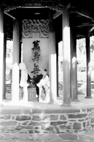 Lucky LUCKY SHD 400 (FF)

English

A black-and-white photograph of a pavilion with stone columns and a tiled roof. The pavilion features a stone tablet with Chinese characters carved into it. Two people, slightly blurred, are standing in front of the tablet, possibly reading or observing it. The background shows more columns and a natural setting with trees.

中文

一张黑白照片，拍摄的是一个带有石柱和瓦屋顶的亭子。亭子内有一块刻有汉字的石碑。两个人站在石碑前，略显模糊，可能在阅读或观察石碑。背景有更多的柱子和自然环境，包括树木