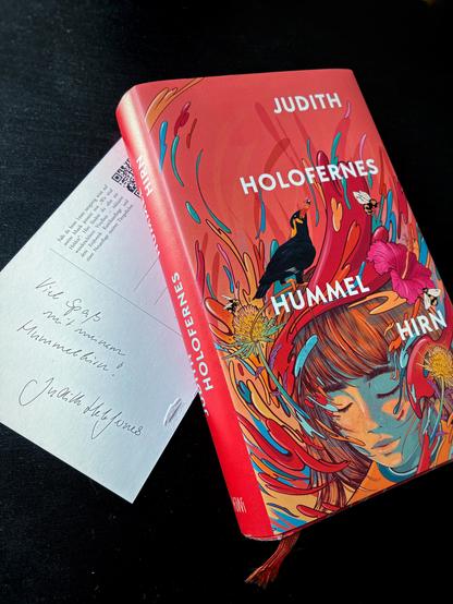 Buchcover: „Hummelhirn“ von Judith Holofernes mit einer Illustration eines Kopfes, der von bunten Farben, Blumen, Insekten und einem Beo umschwirrt wird. Darunter eine Postkarte: „Viel Spaß mit meinem Hummelhirn. Judith Holofernes“
