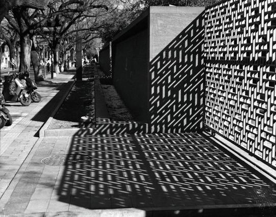 Lucky LUCKY SHD 400 (6x7)

English

A black-and-white photograph of a modern architectural structure. The image features a patterned wall with geometric designs, casting intricate shadows on the ground. Several parked motorbikes are visible on the left side, and a tree-lined sidewalk runs parallel to the wall.

中文

一张黑白照片，照片中是一个现代建筑结构。图片展示了一面带有几何图案的墙，图案在地面上投射出错综复杂的影子。左侧停放着几辆摩托车，墙边有一条种满树的人行道。