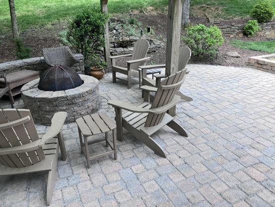 Our cozy back patio with several Adirondack chairs and small side tables arranged around a stone fire pit. A stone quarter wall hems it in nicely, the frog pond just behind. 