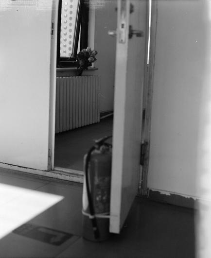 Lucky LUCKY SHD 400 (6x7)

English
A black-and-white photograph of an open door leading into a room. Inside the room, there is a radiator under a window, and a small bouquet of flowers is placed on the windowsill. The floor is tiled, and there is an extinguisher, on the floor near the door.
中文
一张黑白照片，拍摄的是一扇开着的门，通向一个房间。房间内，窗户下面有一个暖气片，窗台上放着一小束花。地面铺有瓷砖，门附近的地上有一个灭火器。