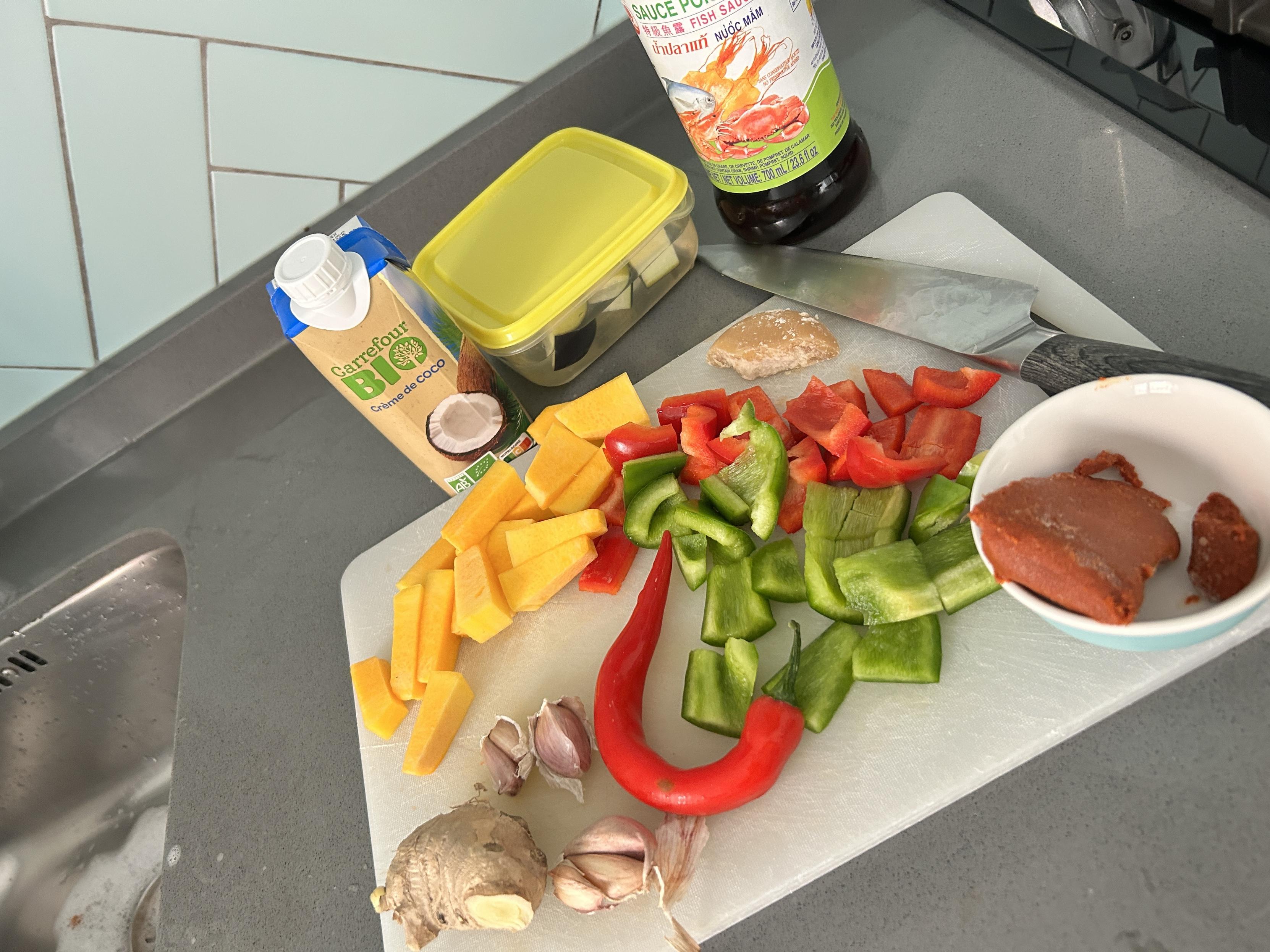 Countertop with all the ingredients for the curry: squash, red and green peppers, palm sugar, chili, eggplant, garlic, ginger, fish sauce, coconut milk, curry paste