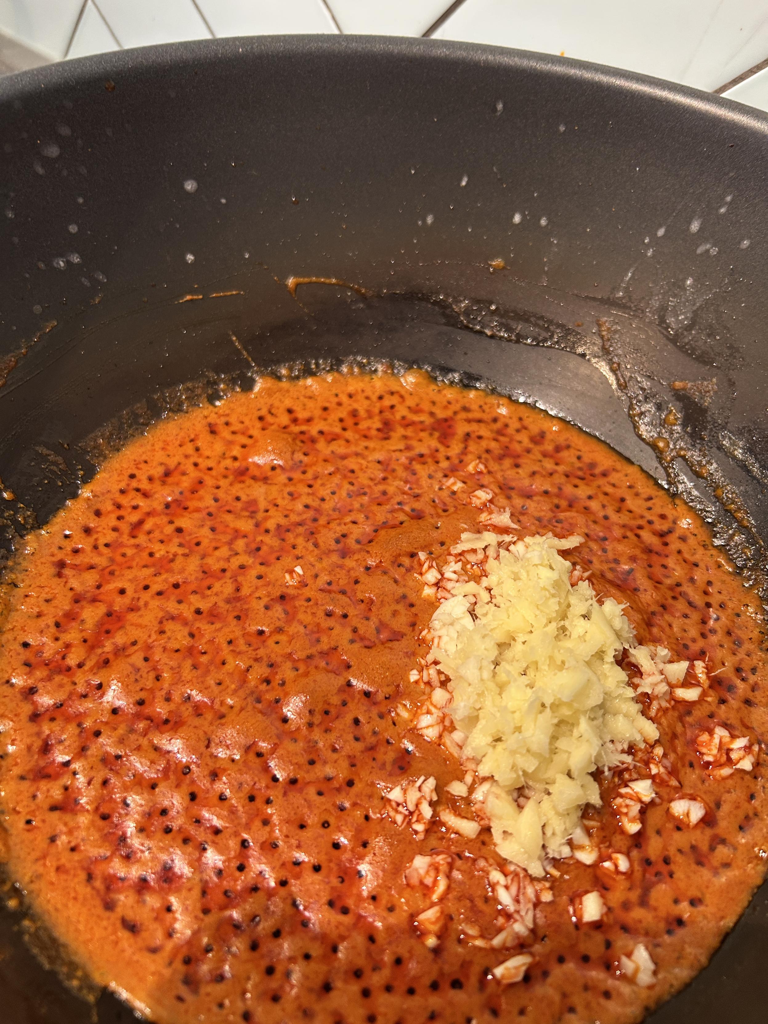 Separated oil in a wok, in bright red, with minced garlic and ginger