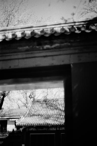 ERA 100 (FF)

English
Black-and-white photograph capturing the intricate details of a traditional Chinese tiled roof. The roof features layered, curved tiles with decorative elements along the edges. Bare tree branches and a traditional Chinese wooden door frame the top front of the image, adding a natural element to the architectural focus.
中文
黑白照片，捕捉到一座传统中式瓦顶的精美细节。屋顶由多层弯曲的瓦片组成，边缘有装饰性元素。光秃的树枝和传统中式木门构成了图像的前上框，为建筑焦点增添了自然元素。