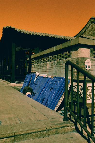 Harman Switch Azure (FF)

English
A traditional Chinese building with a tiled roof and gray brick walls. Blue plastic barriers are stacked against the wall. A stone staircase with a black metal railing leads upward. The sky is orange.
中文
一座传统中式建筑，屋顶铺着瓦片，墙壁由灰色砖块砌成。蓝色的塑料栏杆，堆放在墙边。一个石阶梯配有黑色金属扶手，通向上方。天空呈橙色。