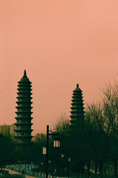 Harman Switch Azure (FF)

English
Silhouettes of two tall, multi-tiered pagodas stand prominently against a gradient orange-pink sky. The pagodas are dark and detailed, with visible tiers and pointed tops. In the foreground, leafless trees and a lamppost are visible, with a few buildings faintly seen in the background.
中文
两座高大的多层宝塔的剪影清晰地映衬在渐变的橙粉色天空下。宝塔呈深色，层次分明，顶部尖锐。前景中可见光秃的树木和一盏路灯，背景中隐约可见几栋建筑。