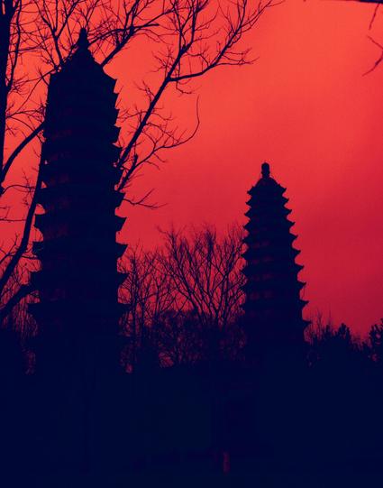 Harman Red 125 (6x7)

##English
Silhouette of two pagodas among bare trees against a deep red sunset sky. The pagodas, with their distinct tiered roofs, stand out against the dark branches. The sky is a rich, deep red with a gradient that darkens towards the top.
##中文
深红色夕阳天空下，两座宝塔与光秃的树木的剪影。宝塔的分层屋顶在深色的树枝中显得格外突出。天空呈现出丰富的深红色，并向上方逐渐变暗。