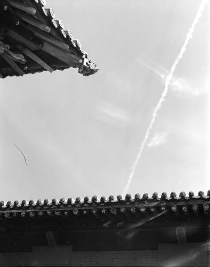 Ilford HP5 Plus 400 (6x7)

English
A black-and-white photograph focusing on the intricate eaves of a traditional Chinese tiled roof. The image captures the detailed craftsmanship of the roof tiles and decorative elements. The sky is visible in the background, with a faint contrail streaking across it.
中文
一张黑白照片，聚焦于传统中式瓦片屋顶的精美屋檐。图片展现了屋顶瓦片和装饰元素的精细工艺。背景中可见天空，还有一条淡淡的飞机尾迹划过天空。
