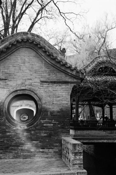 Kentmere PAN 400 (FF)

English
Black-and-white photo of a traditional Chinese brick wall with a circular window. The wall has a curved, tiled roof with ornamental details. Adjacent to the wall is a wooden structure with a sloped roof, supported by columns. Bare trees are visible in the background.
中文
黑白照片，展示一面传统中式砖墙，墙上有一个圆形窗户。墙顶是弯曲的瓦顶，装饰有精美的细节。墙的旁边是一个木结构，斜顶由柱子支撑。背景中是光秃秃的树木。