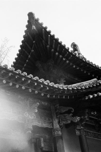 Kentmere PAN 400 (FF)

English
Black-and-white close-up of a traditional Chinese temple roof. The image captures the intricate details of the upturned eaves, which are adorned with small, evenly spaced figurines. The roof tiles are layered, and the wooden structure beneath is visible, showcasing the craftsmanship of the architecture.
中文
黑白特写，拍摄的是传统中式寺庙的屋顶。画面展现了上翘屋檐的精美细节，屋檐上均匀分布着小型雕塑。屋顶瓦片层叠排列，下方的木质结构清晰可见，展现了建筑工艺的精湛。