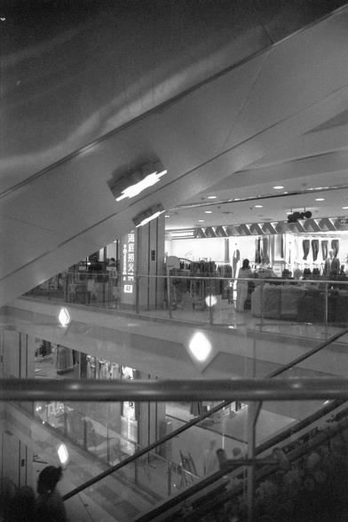 Ilford FP4 Plus 125 (FF)

English
A black-and-white interior shot of a multi-level shopping mall. The image captures escalators, glass railings, and several floors with clothing stores. Signage in Chinese characters is visible, including "4F" and store names. The mall is well-lit with modern design elements.
中文
一张黑白的商场内部照片，拍摄了多层购物中心。画面中有自动扶梯、玻璃栏杆和多个楼层的服装店。可以看到中文字样的标识，包括“4F”和店铺名称。商场灯光明亮，设计现代。