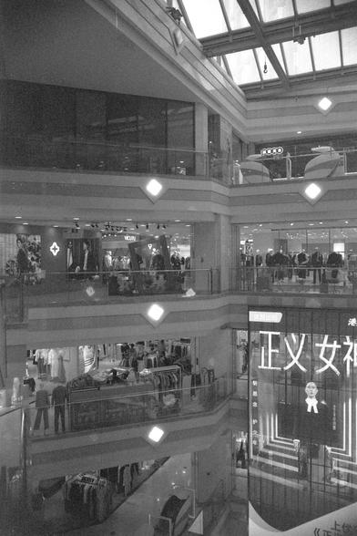 Ilford FP4 Plus 125 (FF)

English
A black-and-white photo of a multi-story shopping mall atrium. The image shows multiple levels with glass railings, escalators, and clothing stores. A large illuminated sign with Chinese characters is prominently displayed on the right side. The mall is bustling with shoppers and has a spacious, open design.
中文
一张黑白的多层购物中心中庭照片。画面展示了多个楼层，配有玻璃栏杆、自动扶梯和服装店。右侧有一个大型发光的中文字标识。商场内顾客络绎不绝，空间开阔，设计现代。
