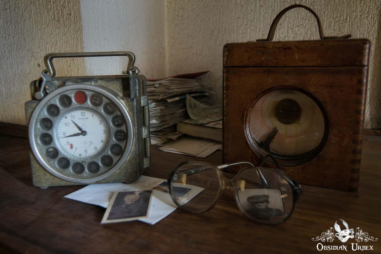 Pigeon racing clocks on table, with small BW photos and old glasses