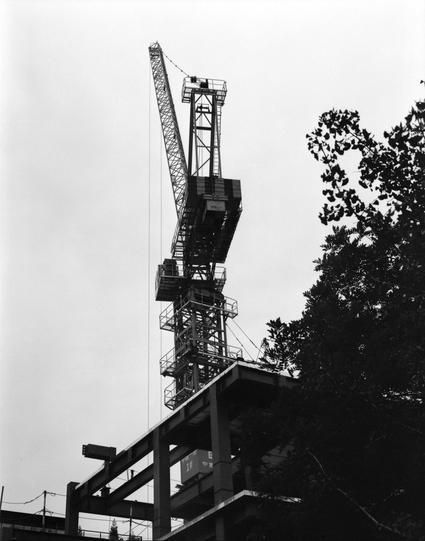 Lucky LUCKY SHD 400 (6x7)

English
Black-and-white photograph of a construction site. A tall tower crane is prominently featured, extending high into the sky. The crane is attached to a partially constructed building with visible steel frameworks and platforms. Trees are visible on the right side of the image, contrasting with the industrial scene.
中文
黑白照片，展示一个建筑工地。图中突出显示了一台高大的塔式起重机，延伸至高空。起重机连接到一栋部分建成的建筑，可以看到钢结构框架和平台。图像右侧可见树木，与工业场景形成对比。