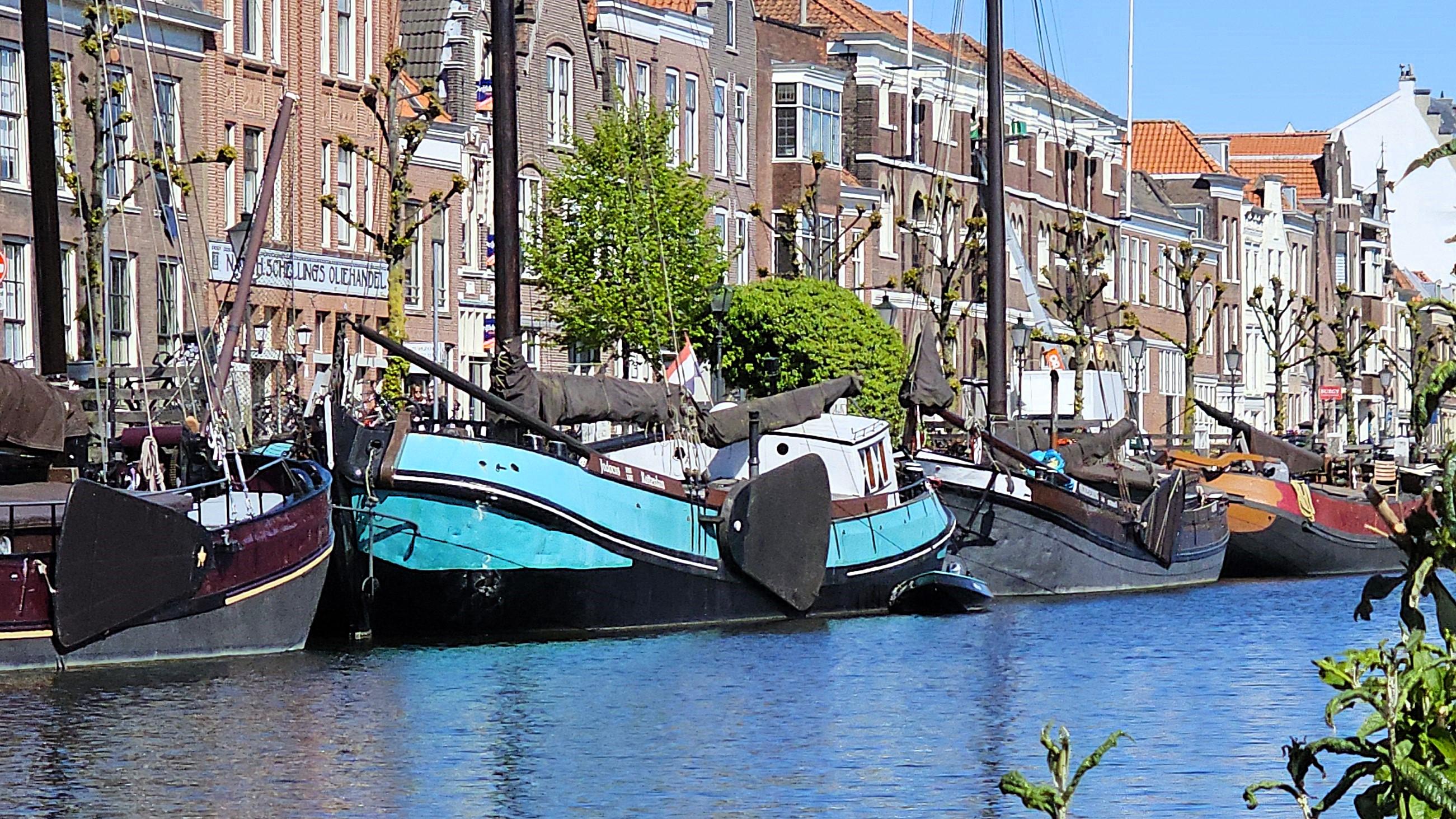 Brightly coloured canal boats tied up in front of historic buildings.