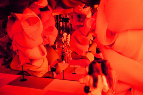 Harman Red 125 (FF)

English
A close-up view of a large, immersive installation composed of red and orange fabric pieces. The fabric is arranged in layered, flowing forms, creating a sense of depth and texture. The lighting is warm and red-toned, enhancing the vibrant colors of the installation. A few people are partially visible, adding a sense of scale to the scene.
中文
一个大型沉浸式装置的特写视图，由红色和橙色的布料片组成。布料以分层、流动的形式排列，营造出深度和质感的感觉。灯光温暖且带有红色调，增强了装置的鲜艳色彩。几个人部分可见，为场景增添了尺度感。