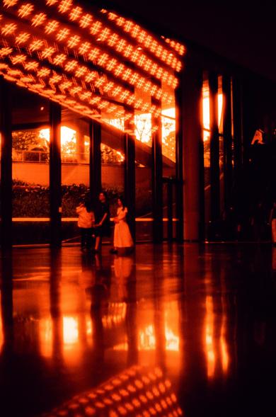 Harman Red 125 (FF)

English
A dimly lit interior space with a highly reflective, polished floor. The ceiling features a grid of red-orange lights forming a geometric pattern. Two people stand near the center, partially silhouetted, with large glass windows in the background revealing a faint view of trees and an outdoor area. The overall atmosphere is warm and moody due to the red-orange lighting.
中文
一个光线昏暗的室内空间，地面高度光滑且具有反光性。天花板上装饰着红橙色的灯光，排列成几何图案。两个人站在中央附近，部分轮廓被光线遮挡，背后是巨大的玻璃窗，透过窗户可以隐约看到户外的树木和区…