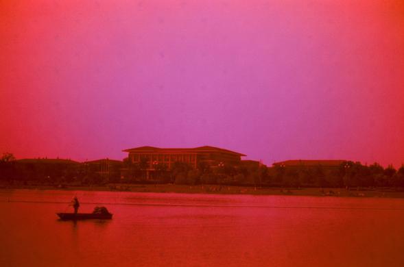 Harman Red 125 (FF)

English
A serene outdoor scene at dusk or dawn, dominated by a deep red-pink sky. A large, multi-story building with a red roof and white walls sits in the background, surrounded by trees. In the foreground, a person stands on a small boat on a calm body of water, creating a peaceful and reflective atmosphere.
中文
黄昏或黎明时分的宁静户外场景，天空呈现深红色和粉红色。背景中有一栋带红色屋顶和白色墙壁的多层建筑，周围环绕着树木。前景中，一个人站在平静水面上的小船上，营造出宁静而沉思的氛围。