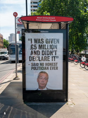 A bus stop in the UK has an ad from Everyone Hates Elon showing a picture of Nigel Farage at the bottom. Text in big black letters says "'I was given 5 million pounds and didn't declare it'- said no honest politican ever"