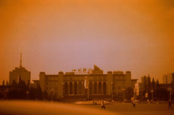 Harman Red 125 (FF)

English
A sepia-toned photograph of a large, grand building with classical architecture, featuring columns and a triangular pediment. The building has a sign with Chinese characters at the top. The sky is hazy, and the scene is bathed in a warm, orange glow. A few people and vehicles are visible in the open square in front of the building.
中文
一张带有暖色调的照片，展示了一座宏伟的古典建筑，建筑上方有中文字样的标志。建筑物有柱子和三角形山墙，天空呈现朦胧的橙色光晕。建筑前方的广场上有几个人和车辆。