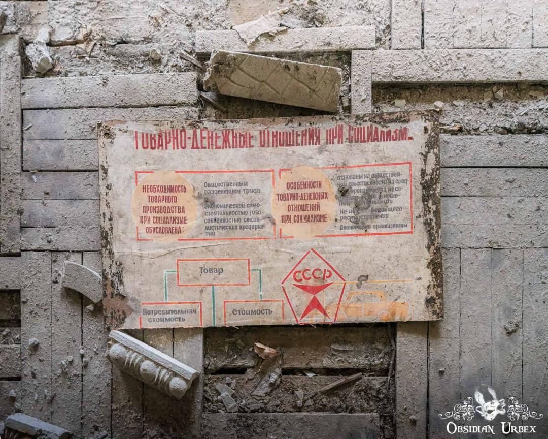 A weathered Soviet-era poster, titled "ТОВАРНО-ДЕНЕЖНЫЕ ОТНОШЕНИЯ ПРИ СОЦИАЛИЗМЕ." (Commodity-Money Relations Under Socialism.). A red star and USSR emblem are visible at the bottom, surrounded by debris.