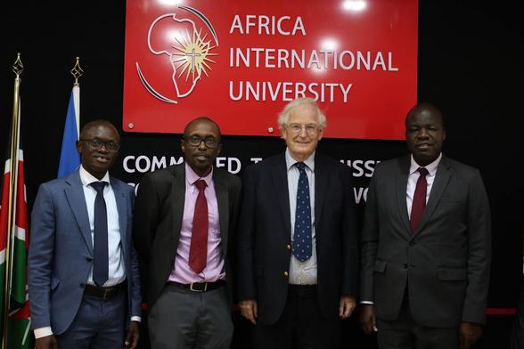 Men in front of a sign for Africa International University