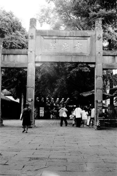 Lucky LUCKY SHD 400 (FF)

##English
A black-and-white photograph of a traditional East Asian archway entrance. The archway is made of stone, with intricate carvings on the pillars. Above the arch, there is a sign with Chinese characters. People are walking through and around the archway, and trees are visible in the background, creating a serene and cultural atmosphere.
##中文
一张黑白照片，展示了一个传统东亚风格的石头拱形入口。拱门的柱子上有精美的雕刻。拱门上方写着汉字。人们在拱门下和周围行走，背景中有树木，营造出一种宁静而富有文化氛围的场景。