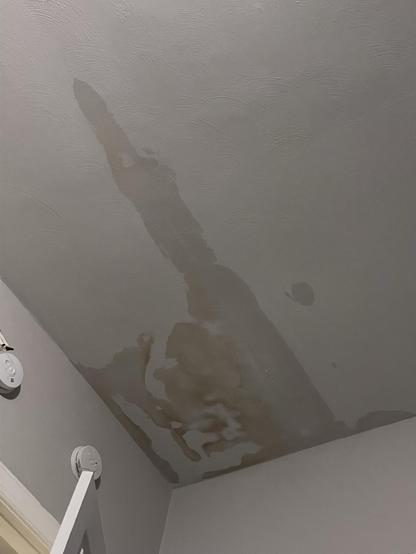 Water damage on a ceiling, with noticeable brown stains and discoloration.