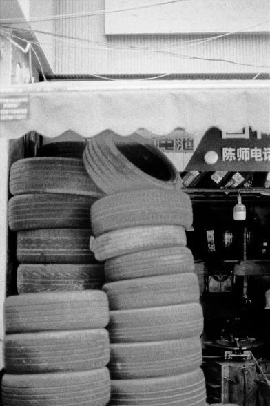 Lucky LUCKY SHD 400 (FF)

English
A black-and-white photograph of a tire shop interior. The image prominently features a tall stack of used tires in the foreground. In the background, there are shelves displaying various automotive products and accessories. A sign with Chinese characters is visible.
中文
一张黑白照片，展示了轮胎店的内部。图像前景是一个高高的废旧轮胎堆。背景中有展示各种汽车产品和配件的货架。还可以看到一个中文标志。