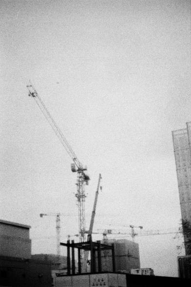 Lucky LUCKY SHD 400 (FF)

English
A black-and-white photograph of a construction site with multiple cranes. The image captures a tall crane in the foreground, with its long arm extended upward. In the background, several other cranes are visible against a hazy sky. The lower part of the image shows the skeletal structure of a building under construction, with concrete pillars and beams.
中文
一张黑白照片，展示了一个建筑工地，有多台起重机。图像前景是一台高大的起重机，其长臂向上延伸。背景中，在朦胧的天空下还可以看到其他几台起重机。图像下方显示了一栋在建建筑的骨架结构，有混凝土柱和梁。