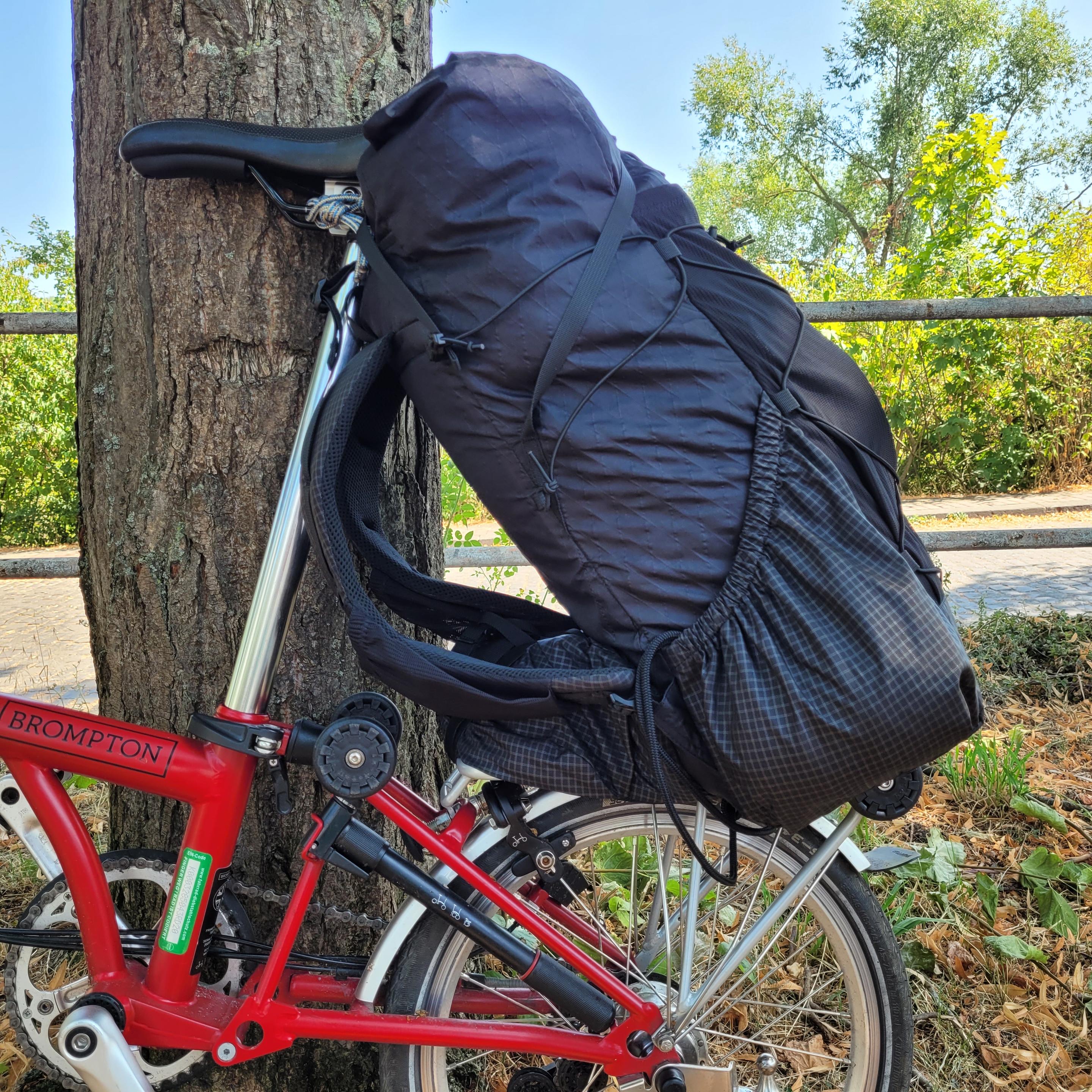 Foto des Rucksacks auf dem Gepäckträger von der Seite. Die schräge Lage ist gut zu sehen. Die Schultergurte hängen lose.